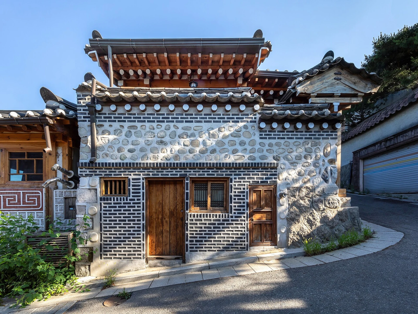 Traditional hanok house with wooden doors along a steeply sloping street in Bukchon Hanok Village Seoul.jpg